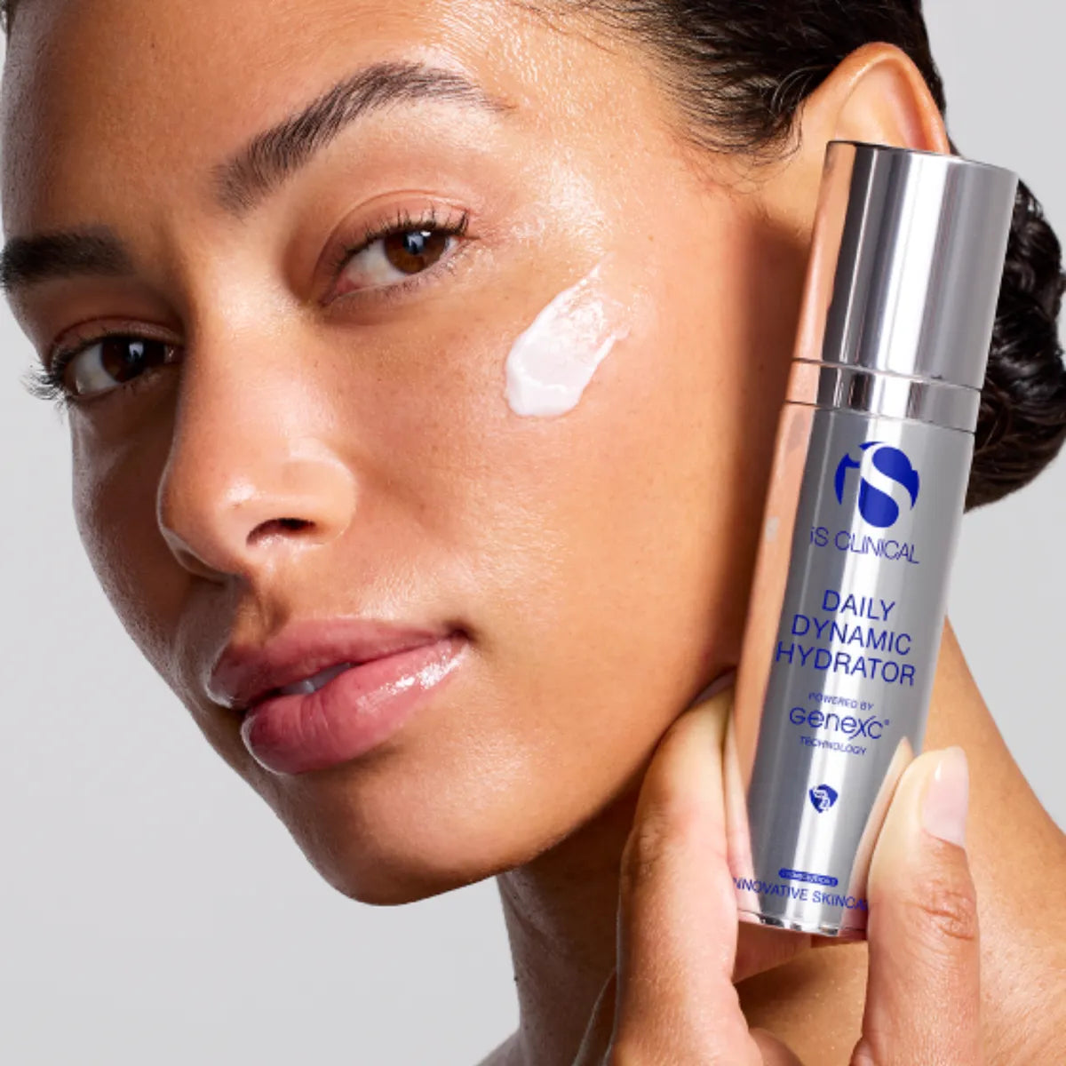 Woman applying skincare product to her face with a bottle labeled 'Daily Dynamic Hydrator' in the foreground.
