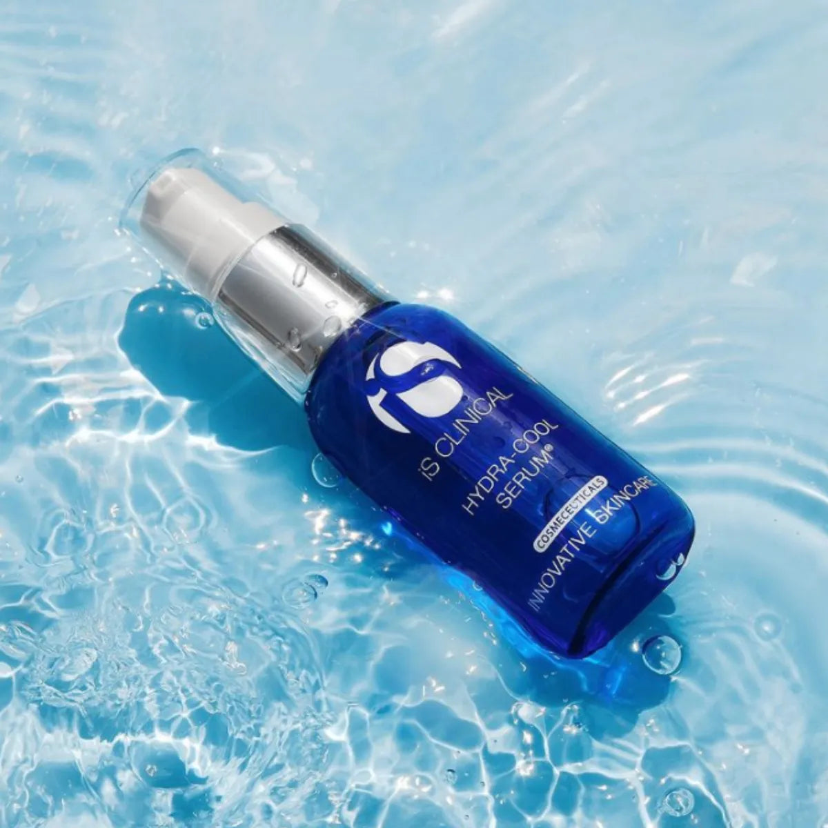 Blue serum bottle with silver cap on a water surface